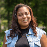 a woman with brown curly hair smiles at the camera